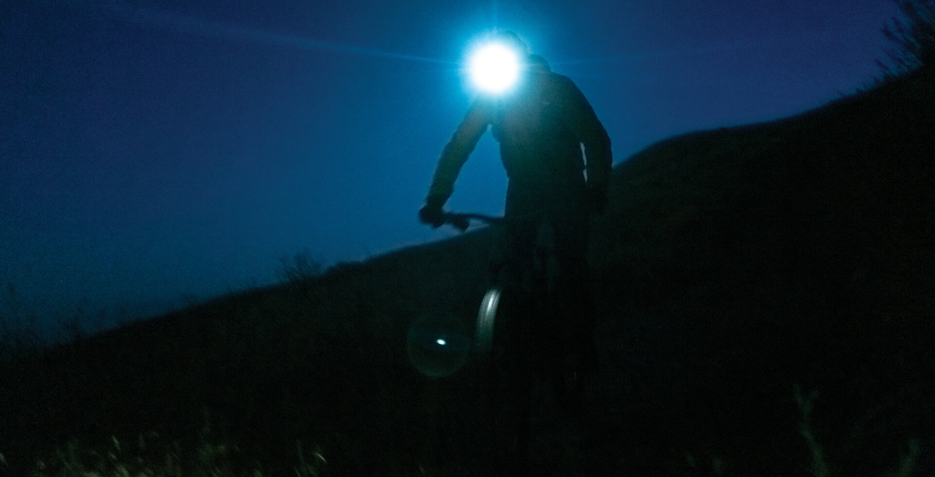So many of the best adventures begin and end in the dark. Writer Dillon Osleger pedals through a sea of blackness on his way to descending the elevational equivalent of the lowest point of the Mariana Trench in one single day of riding.