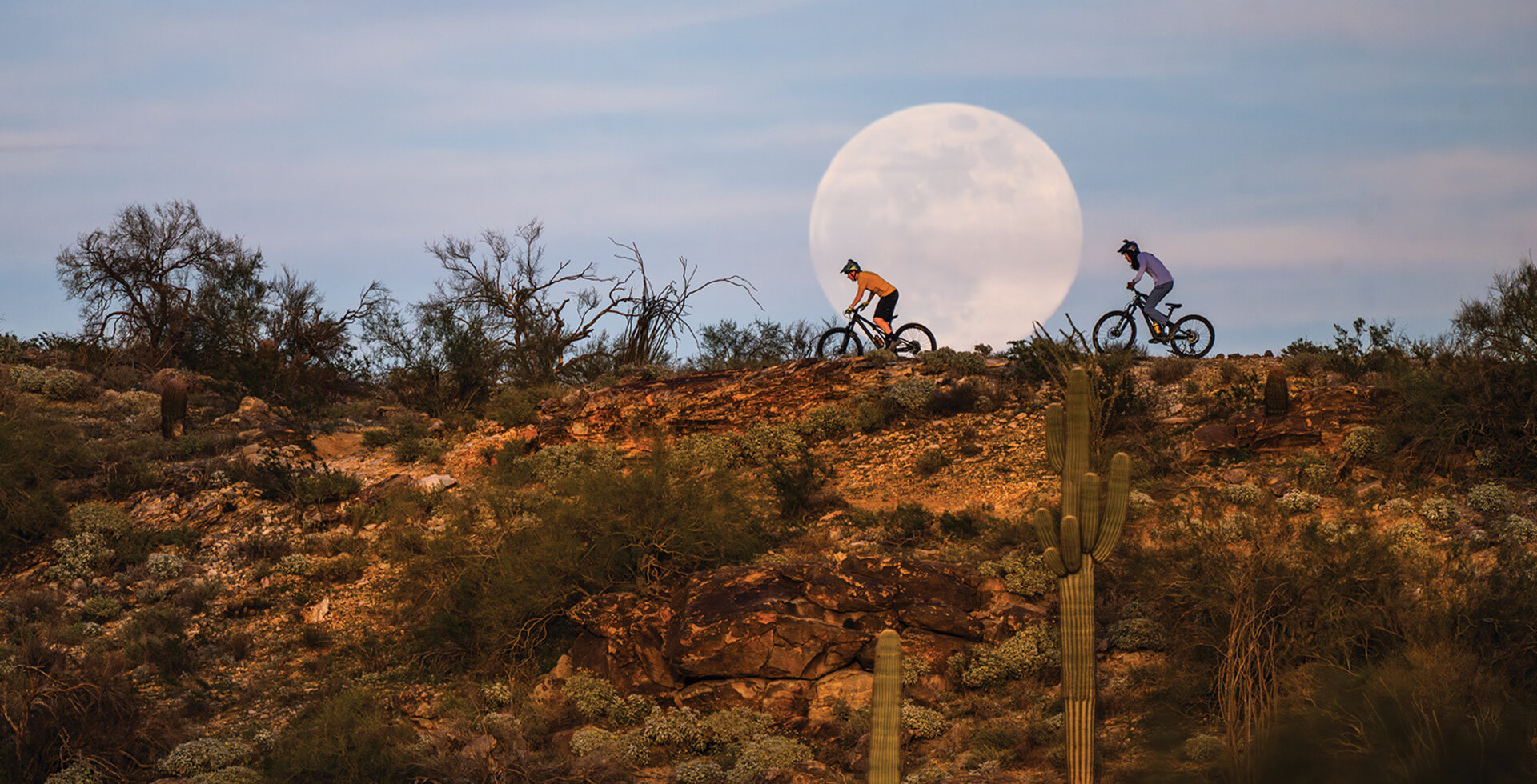 On South Mountain's popular National Trail, riders Bryce Straka (left) and Elliott Milner cruise past the first supermoon of 2026 during an evening spin. Photo: Eric Mickelson | NIKON 1/2000, f/6.3, ISO 500