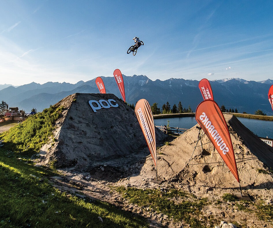 Robin Goomes soars across a massive gap at the 2021 Crankworx World Tour in Innsbruck, Austria. Goomes’ career is full of twists— growing up in the rugged Chatham Islands, time spent in Antarctica, and eventually making the leap to professional mountain biker. Photo: Sven Martin