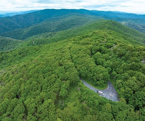 The Take Aim Cycling shuttle van is visible in an open spot in the otherwise dense canopy of the George Washington and Jefferson National Forest. The top of Reddish Knob, where a group of mountain bikers new to backcountry riding would start their journey, is nearby.