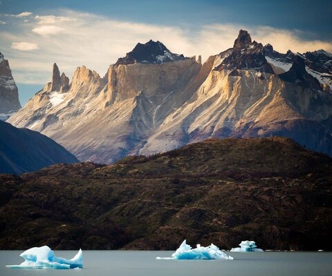 The spires of Torres del Paine National Park in Patagonia, Chile look down on Lago Grey, a glacially fed lake on the west side of the park. Grey Glacier, which is nearly four miles wide and 90 feet thick, often calves large icebergs that float into the lake.